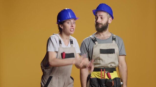 Portrait of construction workers having argument in studio, feeling angry and frustrated about engineering work. Having quarrel and conflict, being mad and unhappy with repair problem.
