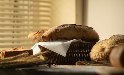 Delicious freshly baked bread in wicker basket and wheat on rustic wooden table.