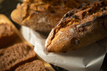 Rustic crusty loaves of bread  with grain in wicker basket on rustic wooden table.