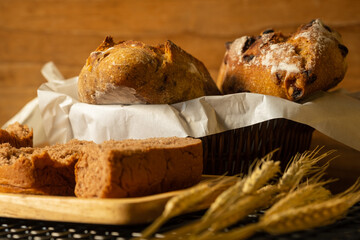 Fresh loaf of rustic traditional bread with wheat grain ear on wooden table.
