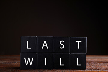 Black cubes with words Last Will on wooden table against dark background