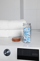 Glass jar with water softener tablets on washing machine in bathroom