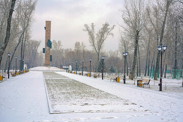 Pedestrian alley in the city park in autumn after the first snow