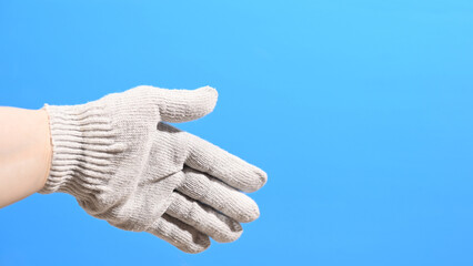 Hand in a working construction cotton glove on a blue background. High quality photo