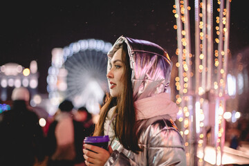 Young thoughtful woman standing in Christmas market in city at night