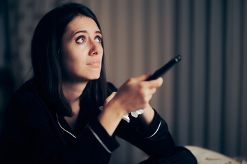 Sad Woman Crying Watching TV Holding a Remote Control. Unhappy lonely girl suffering from love...