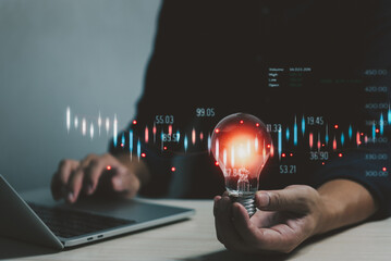 Businessman holding a light bulb in hand innovation concept. Business stock market strategy chart...