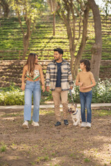 Cheerful family walking a small dog in a park