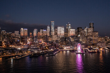 Seattle, Washington, USA - November 2022, night aerial view of illuminated Seattle Downtown and the Waterfront pier area with The Seattle Great Wheel - aerial night view  	