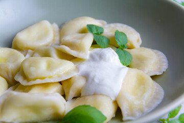 dumplings on a plate with sour cream and fresh green basil leaves 