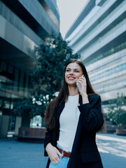 Fototapeta premium Woman with phone in hand smiling with teeth and talking on the phone in front of the city, happiness lifestyle and business