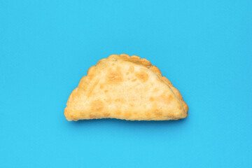 Fresh toasted cheburek on a light blue background.