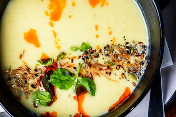 A top-down view of pumpkin soup in a round dark bowl