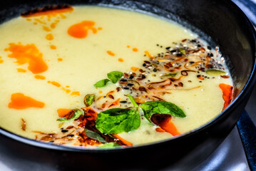 A side on view of pumpkin soup in a round dark bowl