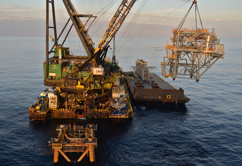 Offshore construction -workers prepare a platform jacket for a riser access truss or RAT aerial showing the derrick barge DB30 and aheavy lift barge with the topside upon it.