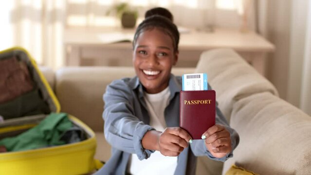 Young happy african american woman showing passport with tickets to camera and gesturing thumb up, free space