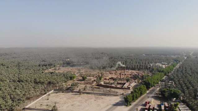 Aerial view of the dates farm in Khairpur Sindh near the highway and a brick factory with smoke in the background.
