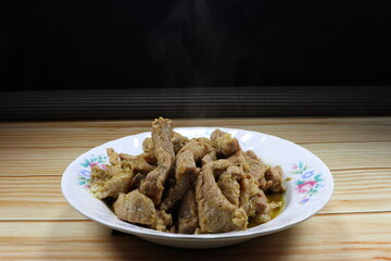Traditional fried spicy sliced pork with green curry and pepper serving on the plate. Famous appetizer menu in Asian restaurant. 