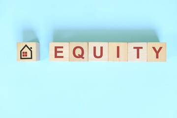 Equity concept in real estate. Wooden blocks typography on blue background.