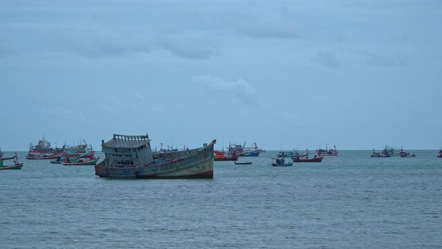 A large fishing boat stranded in Samae San Beach Chonburi Thailand.. fishing boats and barges moored in Samaesan harbor .that shelters waves and storms. .Cargo and fishing boats are therefore parked.