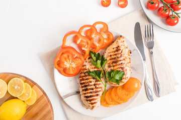 a plate with fried chicken breast, vegetables on a cloth napkin and a white table. top view....