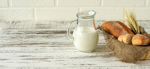 Sliced rye bread on wooden cutting board next to jug with milk. Tasty food close up. Homemade baked...