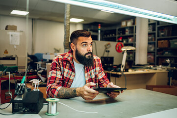 Electronics engineer working in a professional workshop and using a tablet