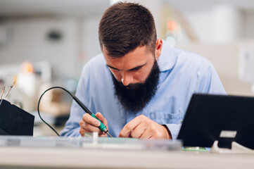 Electronics engineer working in a workshop with tin soldering parts