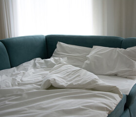 Comfortable sofa-bed with soft white blanket and pillows, closeup