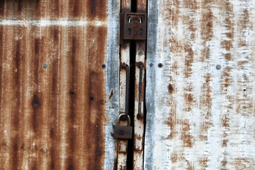 A rusty padlock hangs on a closed gate.
