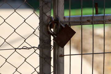 A rusty padlock hangs on a closed gate.