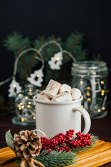 Christmas drink hot chocolate with marshmallows at festive illuminated decoration. Selective focus
