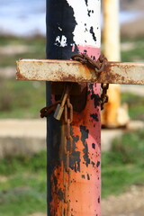 A rusty padlock hangs on a closed gate.