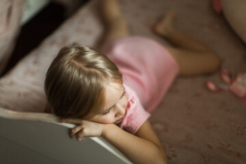 little girl lies on her bed in the children's room