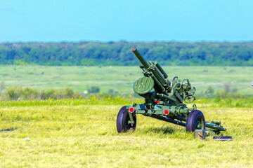 a small artillery cannon stands in a field on a summer day