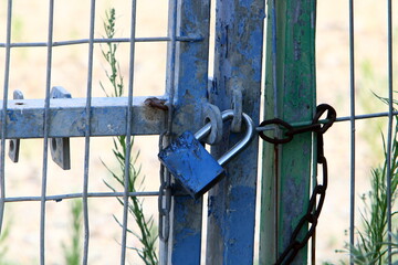 A rusty padlock hangs on a closed gate.