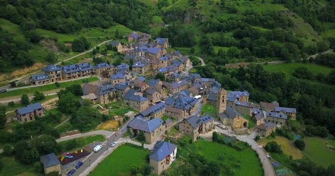 Huts and cottages at ancient village of Durro in Boi valley, amidst huge mountains of Pyrenees, Spain. Aerial.
