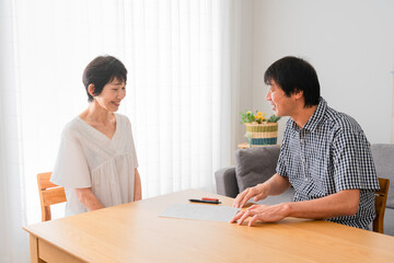 Fototapeta premium ミドル女性に婚姻届けを差し出すミドル男性 熟年結婚イメージ