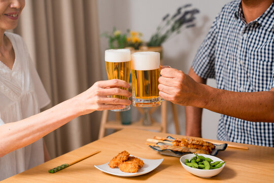 ビールで晩酌をするミドル女性とミドル男性　夫婦の食事イメージ