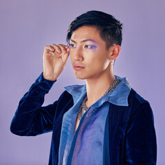 Punk, rock or gay man with eyeshadow, makeup and cosmetics, vintage or retro fashion clothes on a purple background for pop art style. Asian lgbtq identity model in studio for creative color mockup