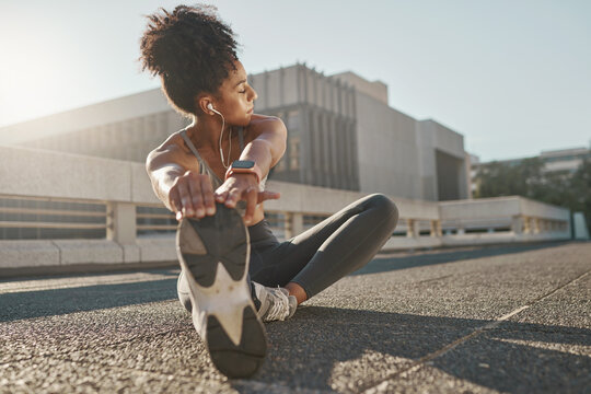 Fitness, city and woman stretching her legs in the street before a cardio workout, running or training. Sports, health and lady doing a warm up stretch for an outdoor exercise in the urban town road.