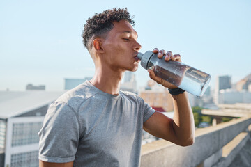 Fitness, exercise and man drinking water in city after running, training or cardio workout. Health, wellness and hydration of sports male from India resting or on break after marathon or sprinting. - obrazy, fototapety, plakaty