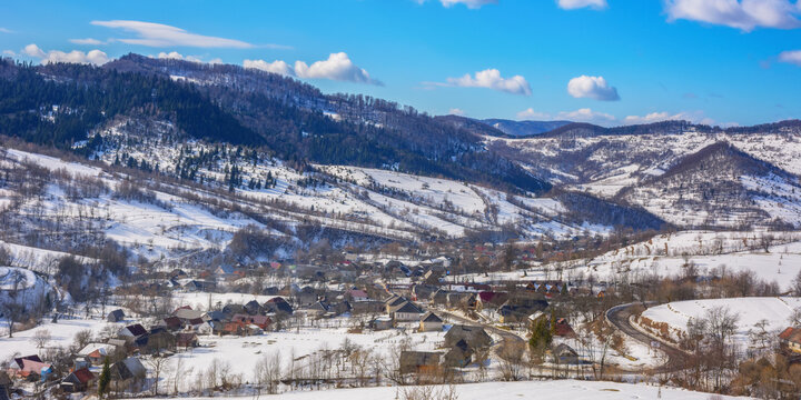 carpathian rural valley in winter. wonderful mountain landscape with village on a sunny day. snow covered fields on the hills