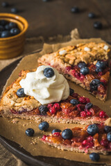 Berry galette with fresh blueberries and whipped cream on a rustic wooden table
