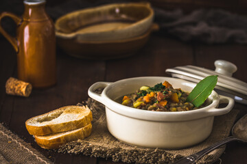 Bowl of lentil stew, toasted bread and bay leaf on rustic wooden table
