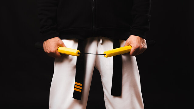 Close up photo of man in kimano holding nunchaku