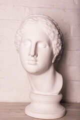 Plaster head of the statue against the background of a white brick wall