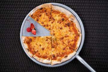 Flat lay or top view shot of a pizza pan with strawberries on a black knitting table