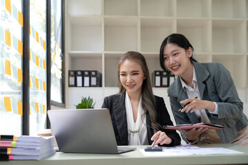 Two young Asian business woman talk, consult, discuss working with new startup project idea presentation analyze plan marketing and investment in the office.
