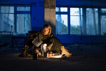 Post-apocalypse. a young woman sits on the floor of an abandoned building filtering heavy water through a makeshift filter. concept of a man hiking in a post-apocalyptic world looking for food.